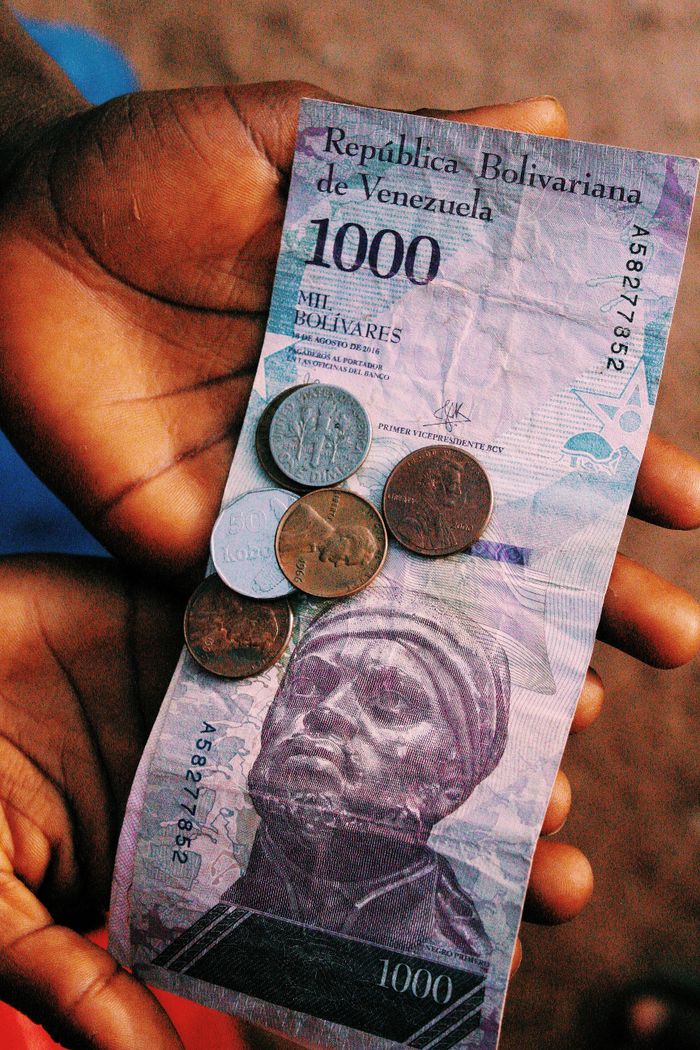 Services Close-up of hands holding a 1000 Bolivar banknote with coins, capturing the essence of Venezuelan currency.