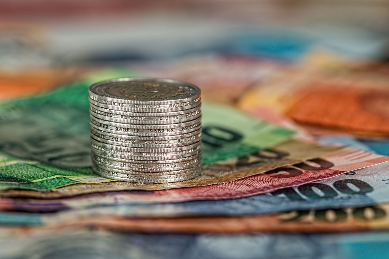 Services A stack of coins on top of various colored banknotes, symbolizing finance and currency.