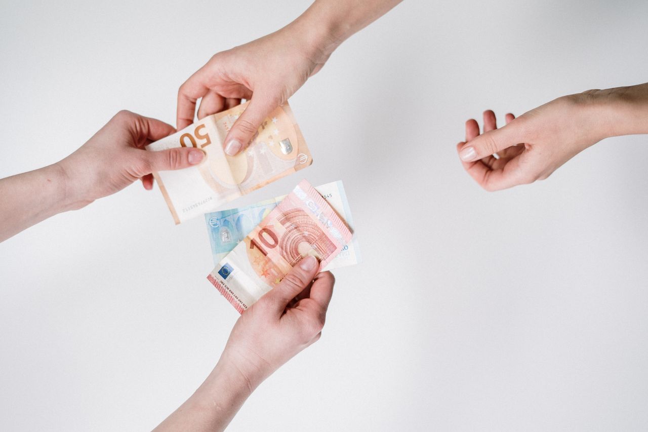 About Close-up of hands exchanging euro banknotes, symbolizing currency trade and financial transactions.